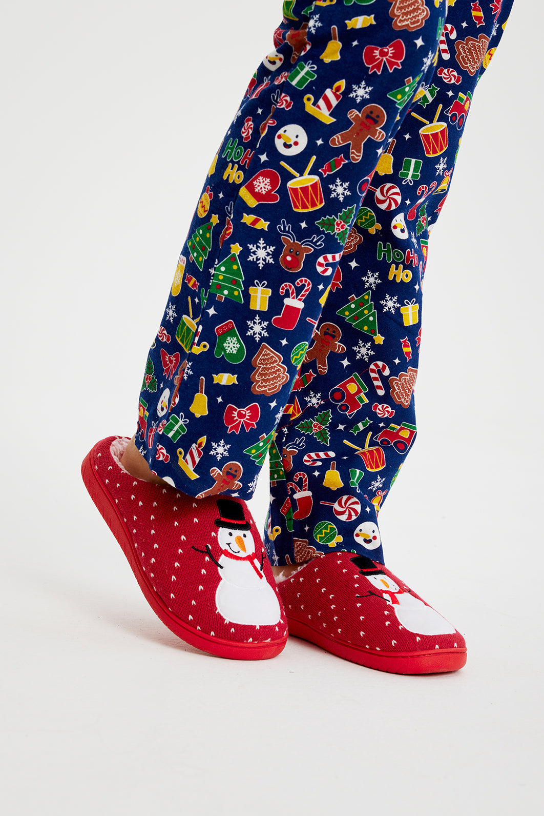 Een paar benen met rode kerstpantoffels aan.