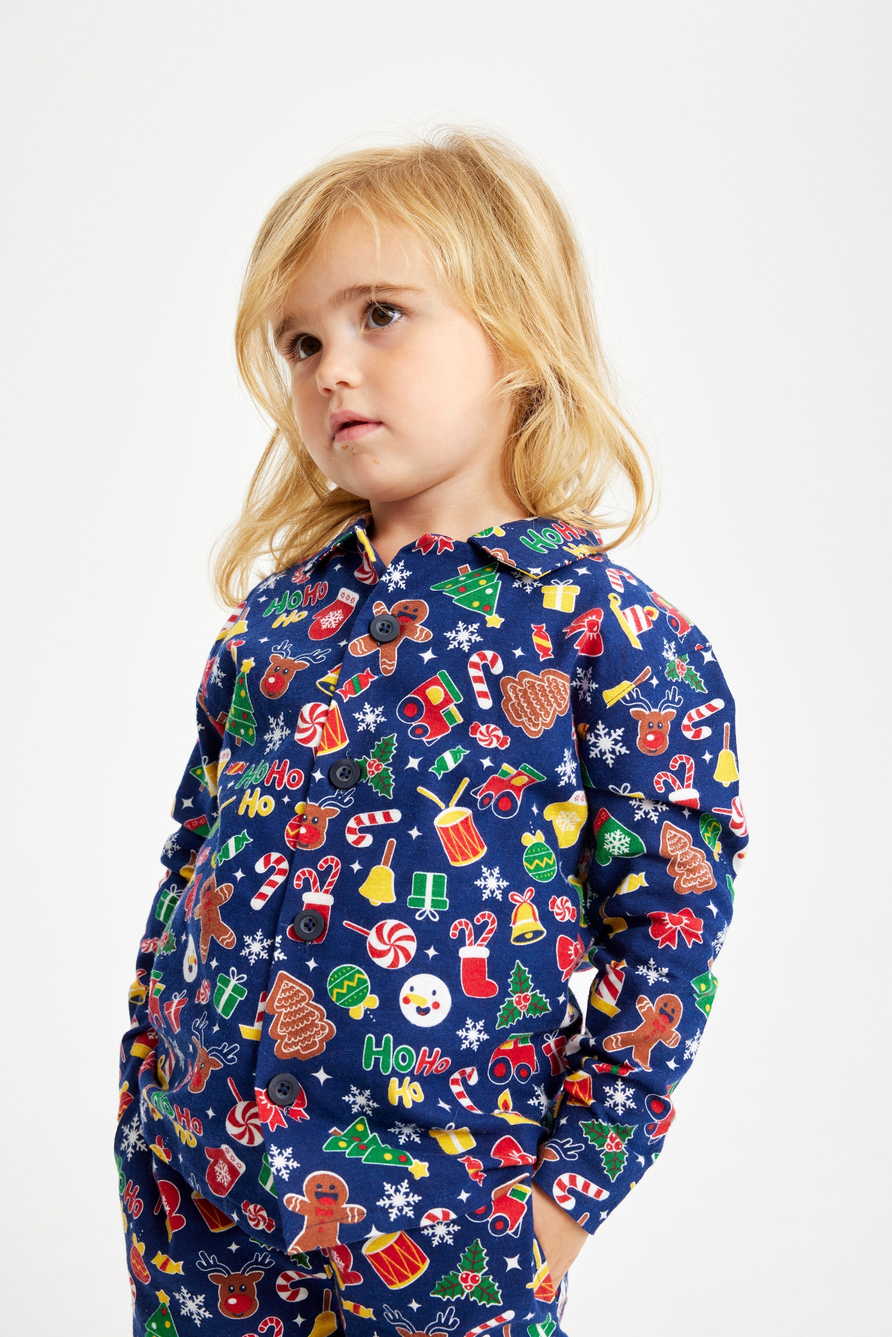 Een poserend kind in een blauwe kerstpyjama.