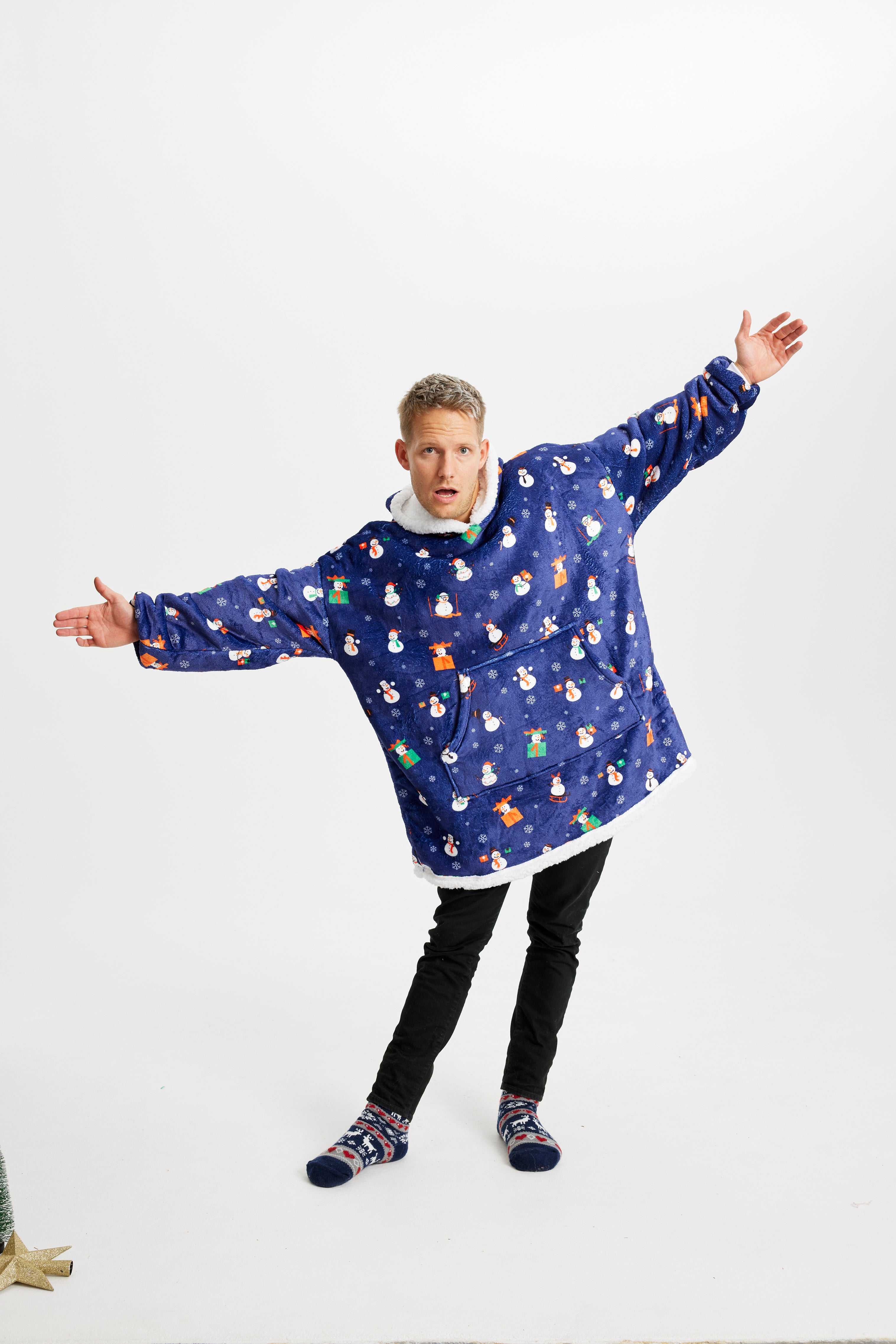 Een poserende man die een blauwe kerst hoodie met sneeuwmannen draagt.