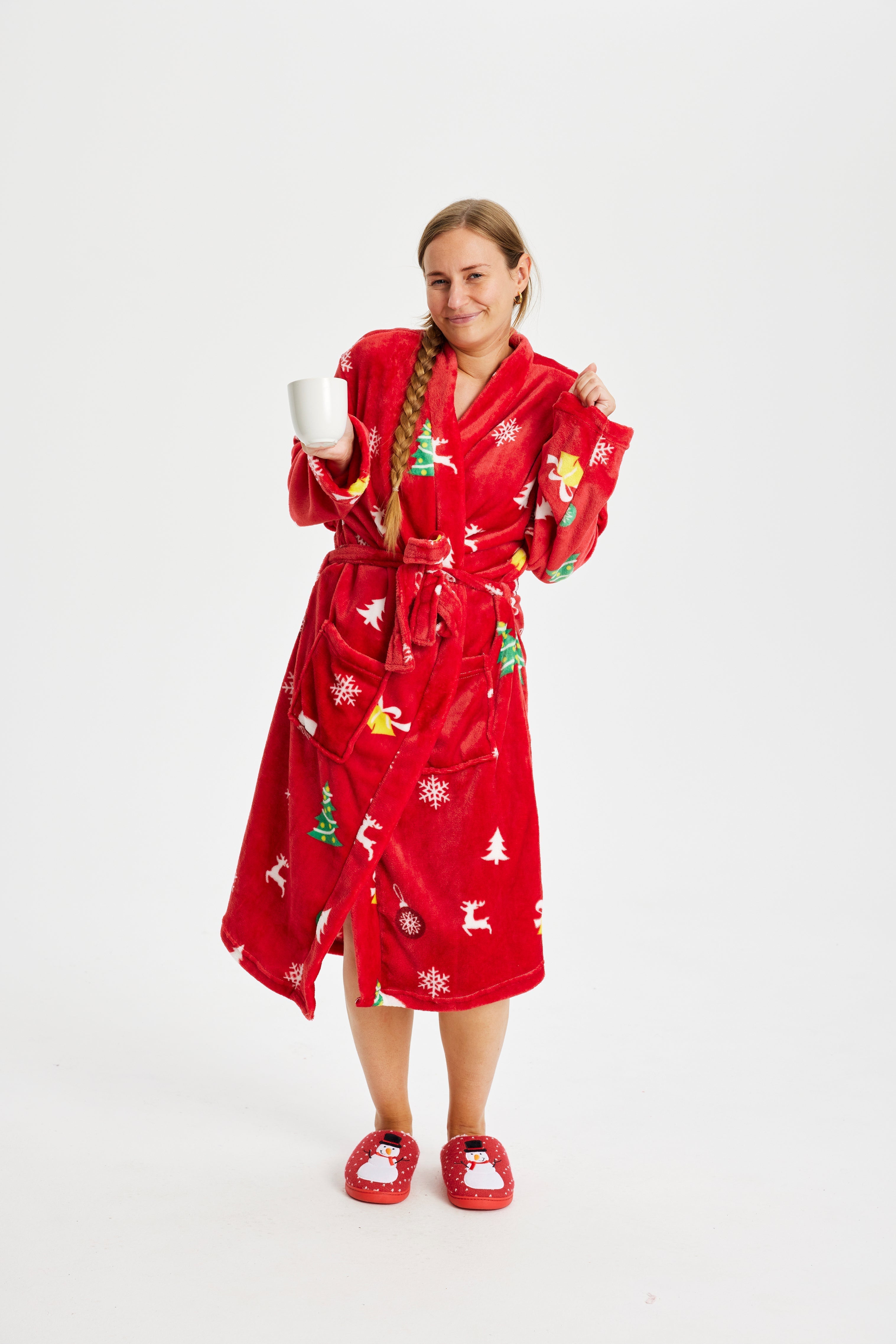 Een vrouw in een rode kerstbadjas met kerstbomen erop.