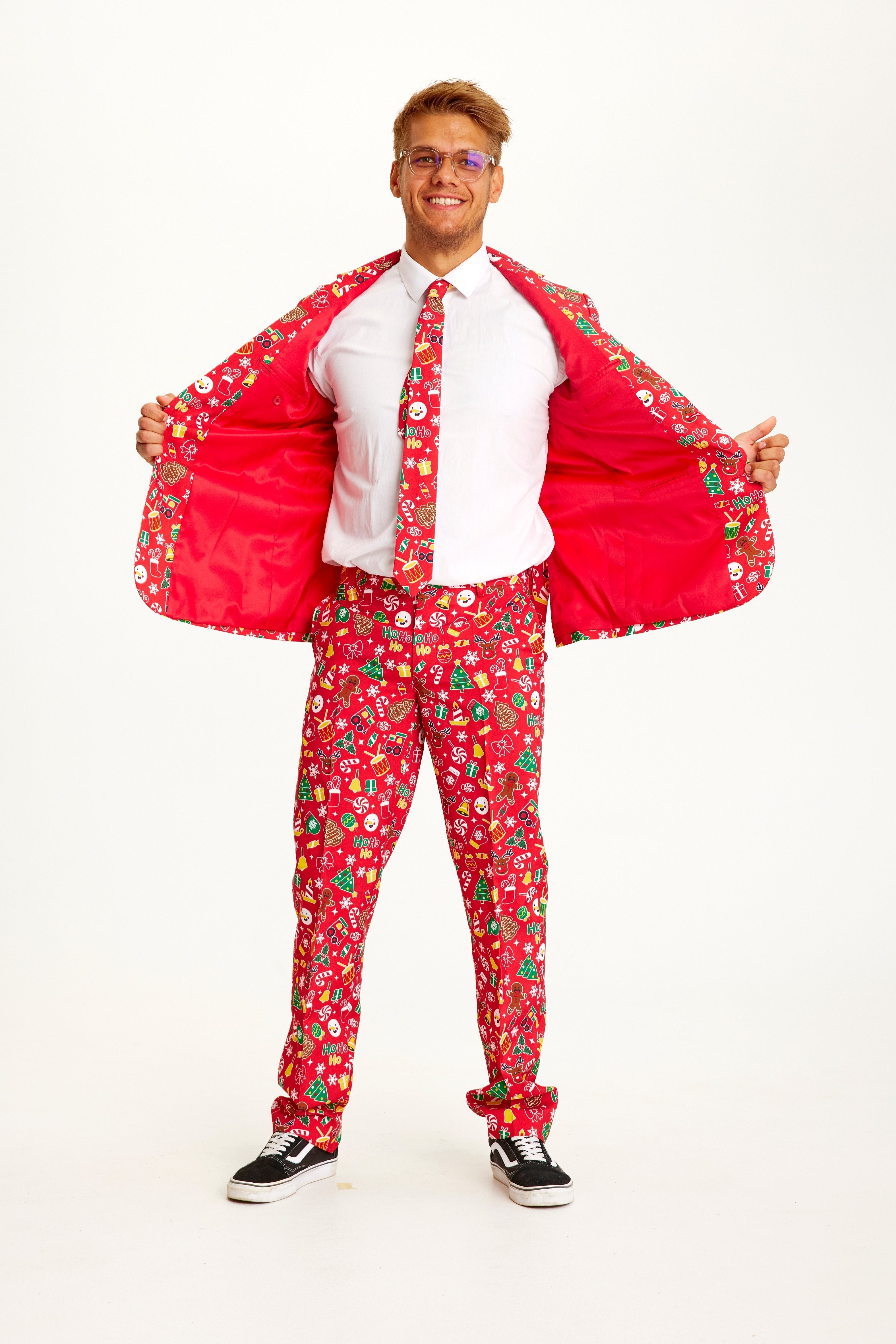 Een poserende man in een rood pak met een kerstpatroon.