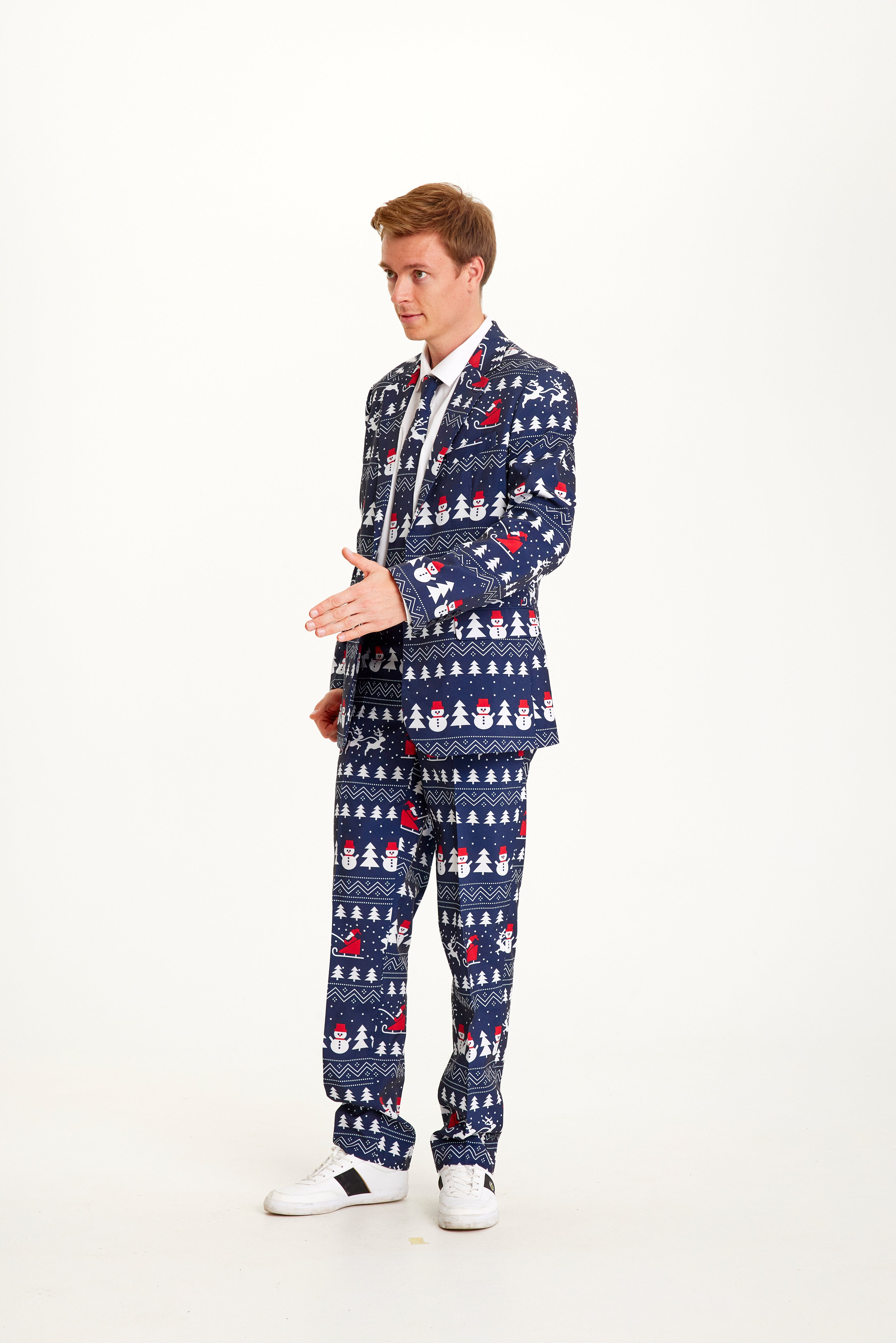 Een poserende man in een blauw pak met een kerstpatroon.